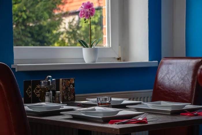 Orchidee auf der Fensterbank über einem gedeckten Tisch