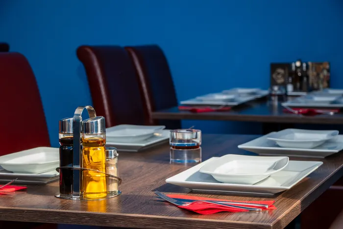 Gedeckter Tisch mit Öl und Essig, weißen Tellern und roten Servietten