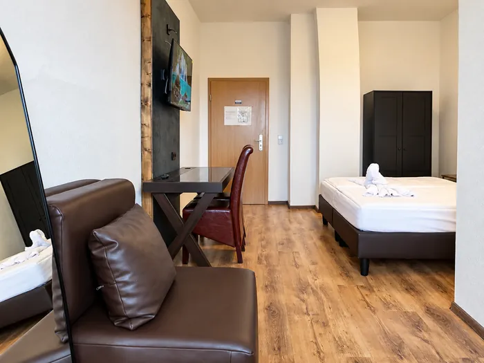 Ledersessel und Schreibtisch, dahinter das Bett