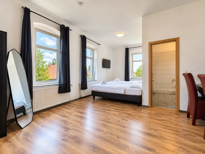 Helles Eckzimmer mit hohen Fenstern und Holzboden