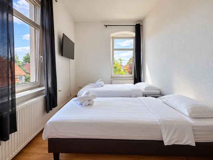 Doppelbett und Einzelbett unter den Fenstern