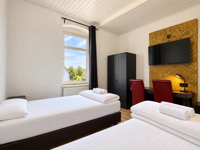 Zimmer mit Einzelbetten und goldener Tapetenwand